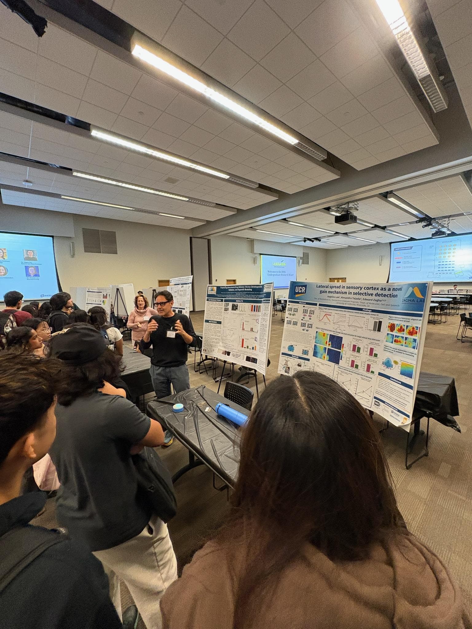 A researcher explaining a scientific poster to a group of students at the LabLink mixer